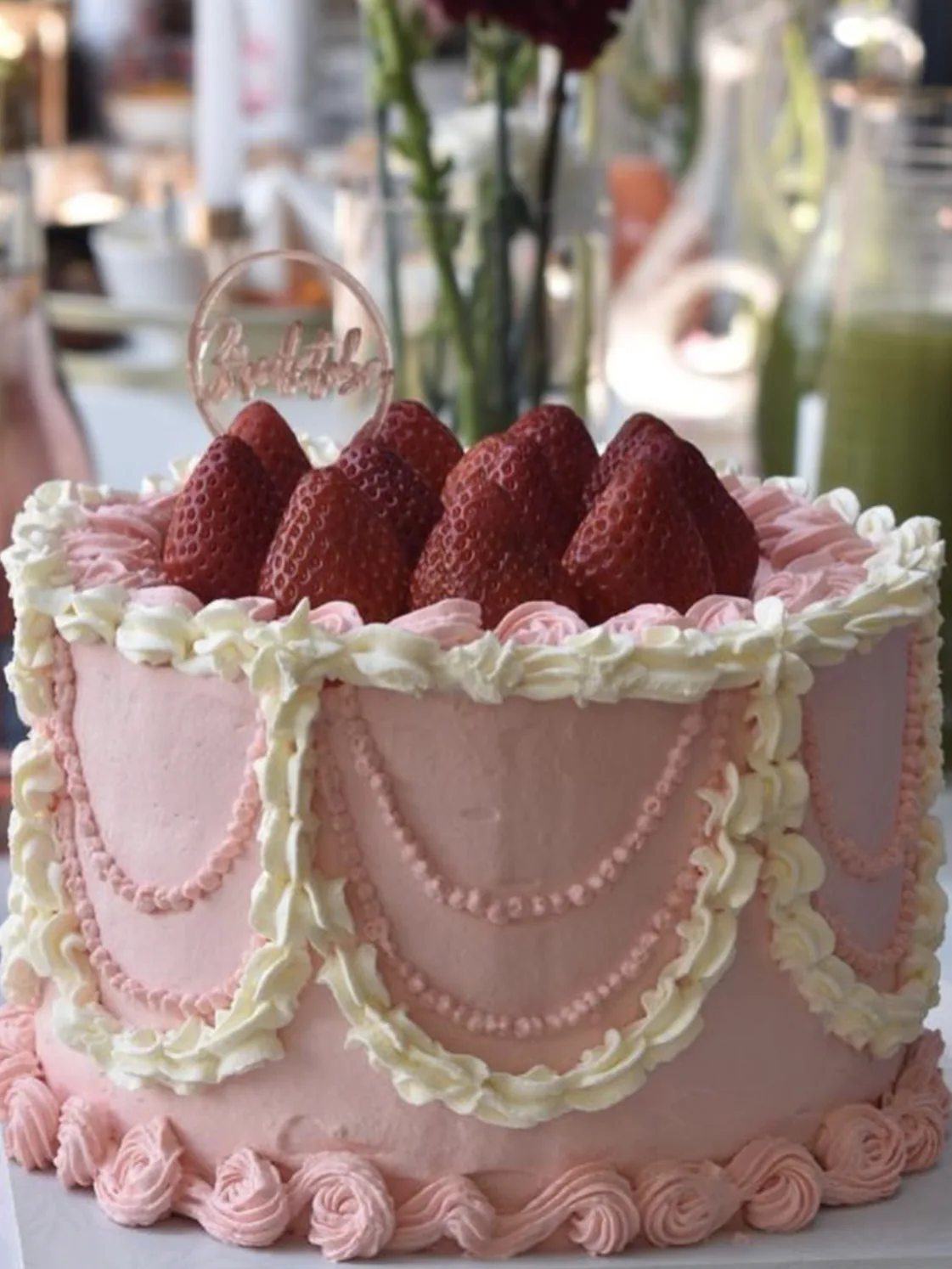 A pink vintage-style cake with piped pearl swags and fresh strawberries on top
